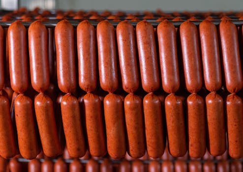 Close-up view of neatly arranged sausages hanging in a production facility.