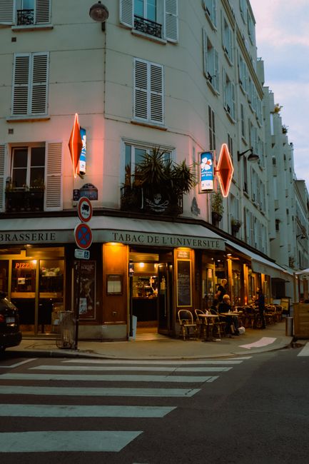 Charming corner café in Paris with glowing neon lights at twilight, offering a warm, inviting atmosphere.