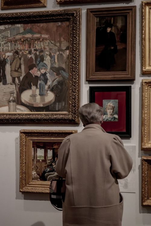 Free A lone visitor in Paris stands captivated by classic artworks in a museum gallery. Stock Photo