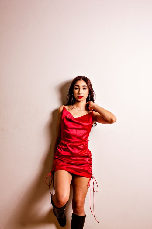 Free Elegant woman in a red satin dress leaning against a wall, exuding confidence and style. Stock Photo