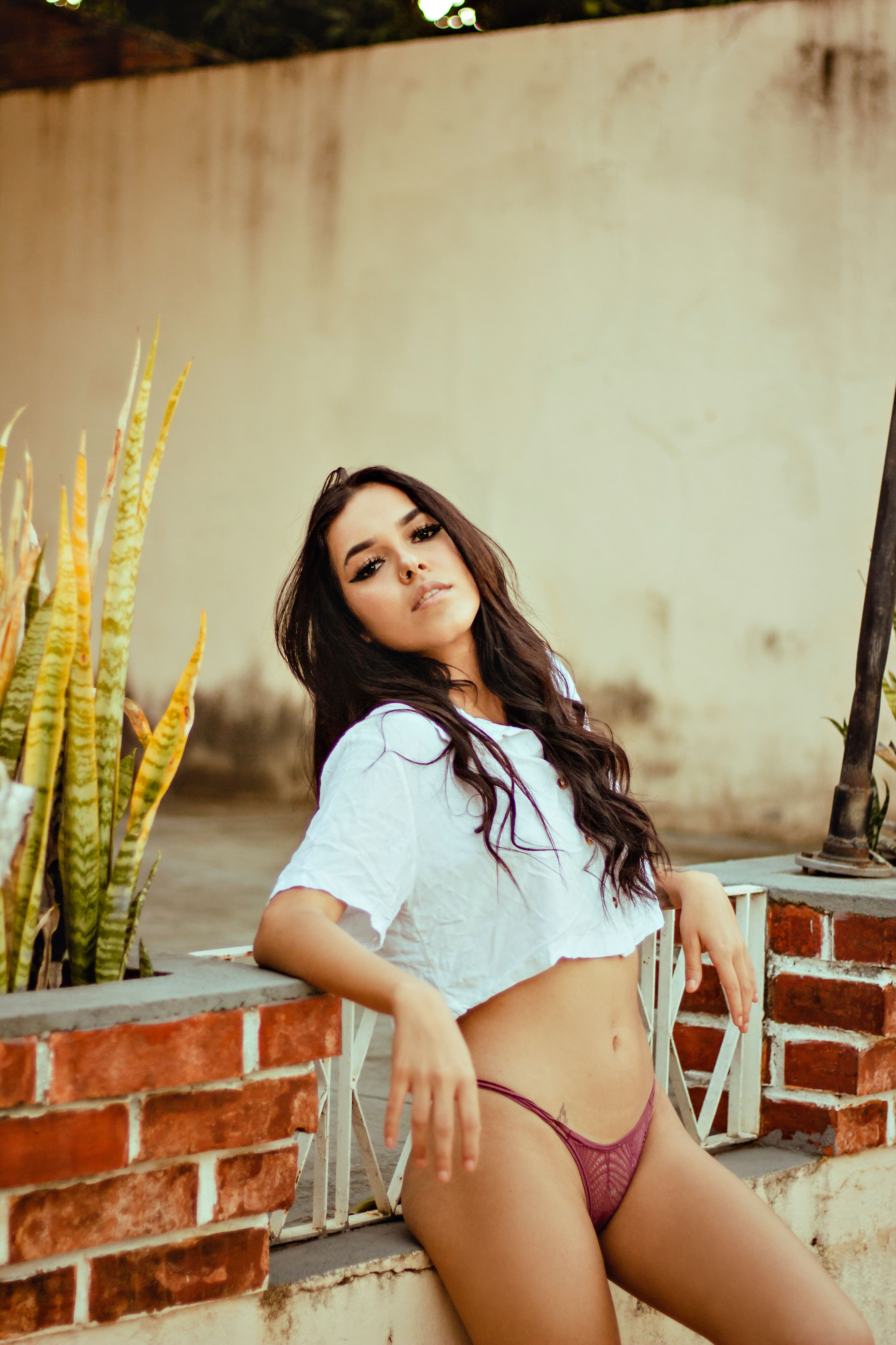 Stylish woman posing outdoors in a white top and underwear, exuding confidence.