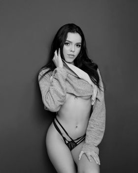Black and white portrait of a woman posing in studio, wearing a knitted sweater.