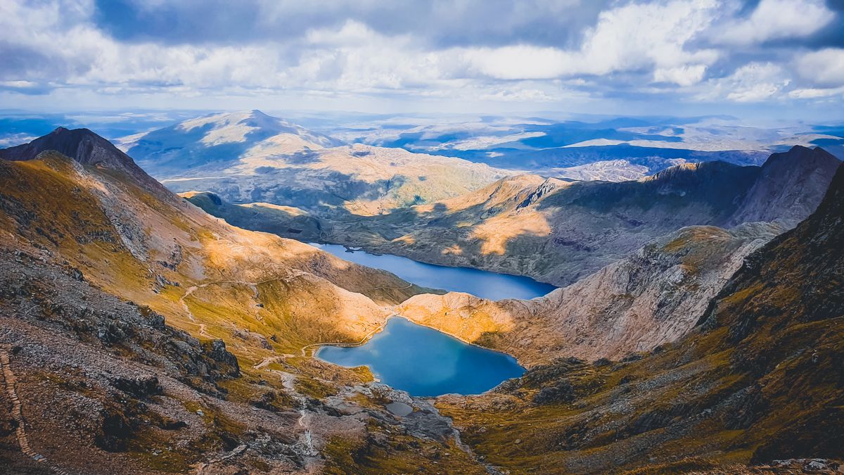 Snowdonia mountain range with scenic lake and rolling hills in Wales