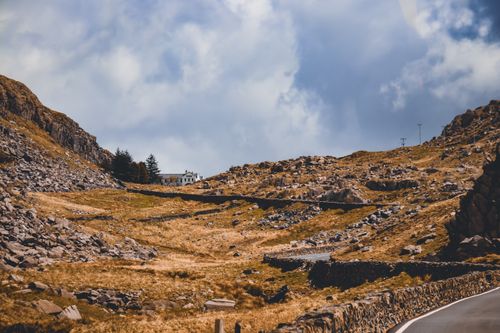 Free Explore a rocky mountain landscape featuring a winding road under a dramatic sky. Stock Photo