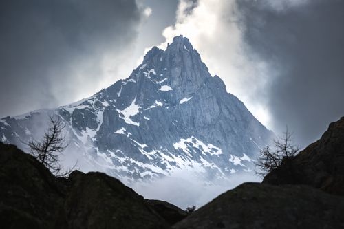 Free A dramatic view of a snow-capped mountain peak surrounded by clouds. Stock Photo