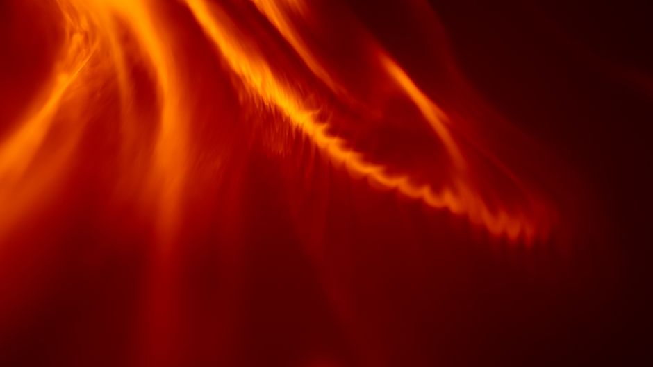 An abstract image featuring dynamic orange and red light textures, resembling flames.