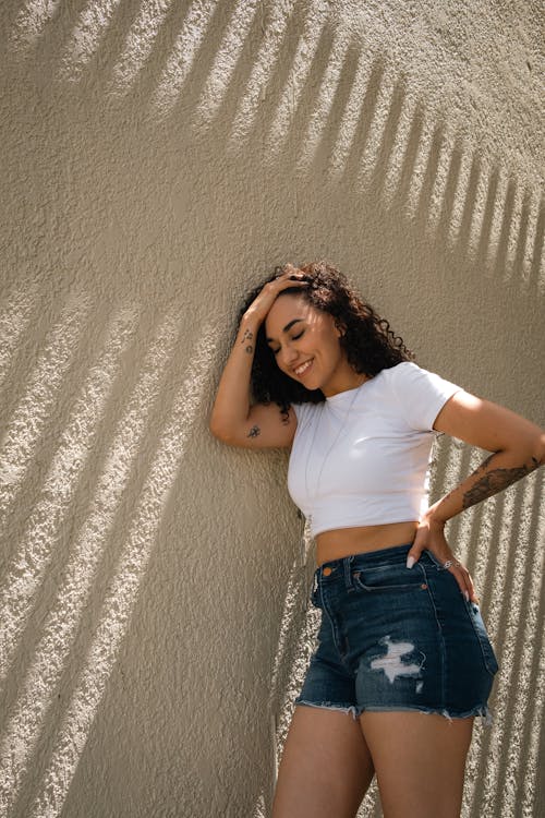 Woman in White Crop Top Leaning on a Wall