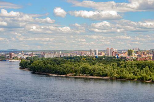 Free A scenic aerial shot of a city skyline with a river in the foreground and clouds above. Stock Photo