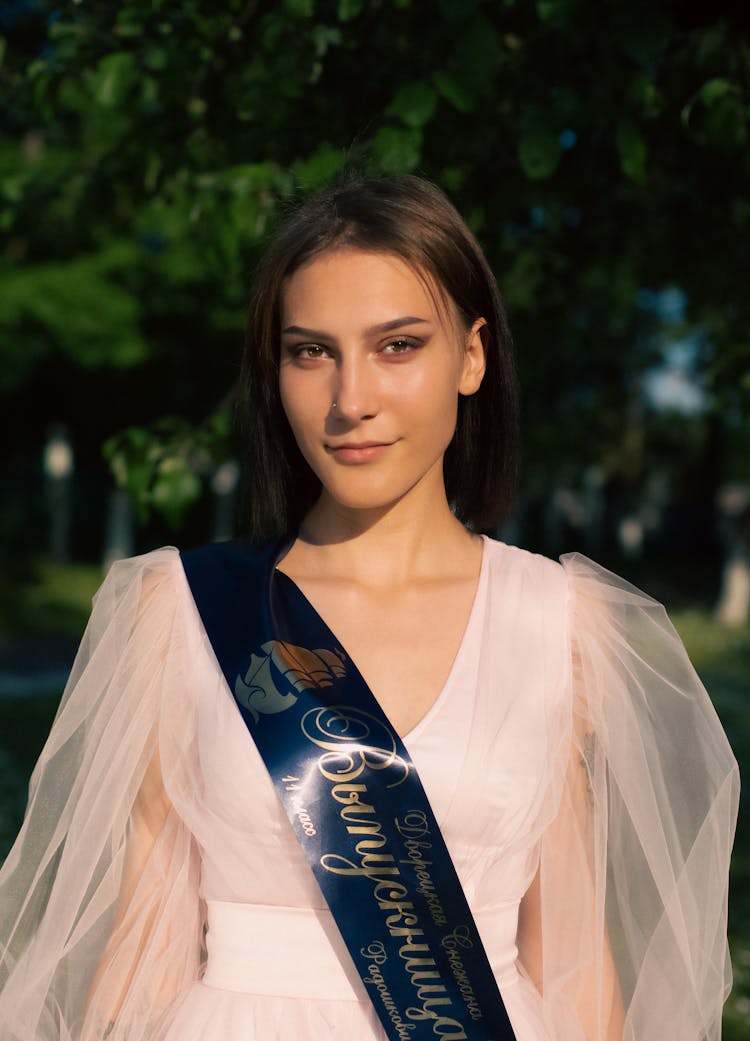 A Woman In White Dress Wearing Blue Sash
