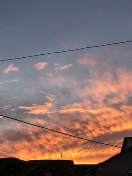 Captivating sunset sky with vivid orange and pink clouds above silhouetted buildings.