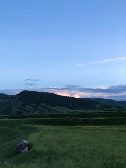 Free Serene landscape of green hills and mountains during twilight with a clear sky. Stock Photo