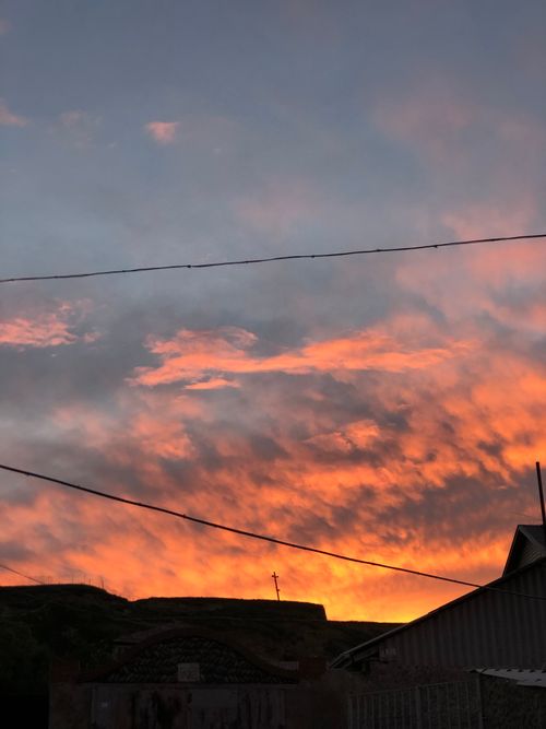 Free Stunning sunset with vibrant orange clouds and silhouetted rooftops. Stock Photo