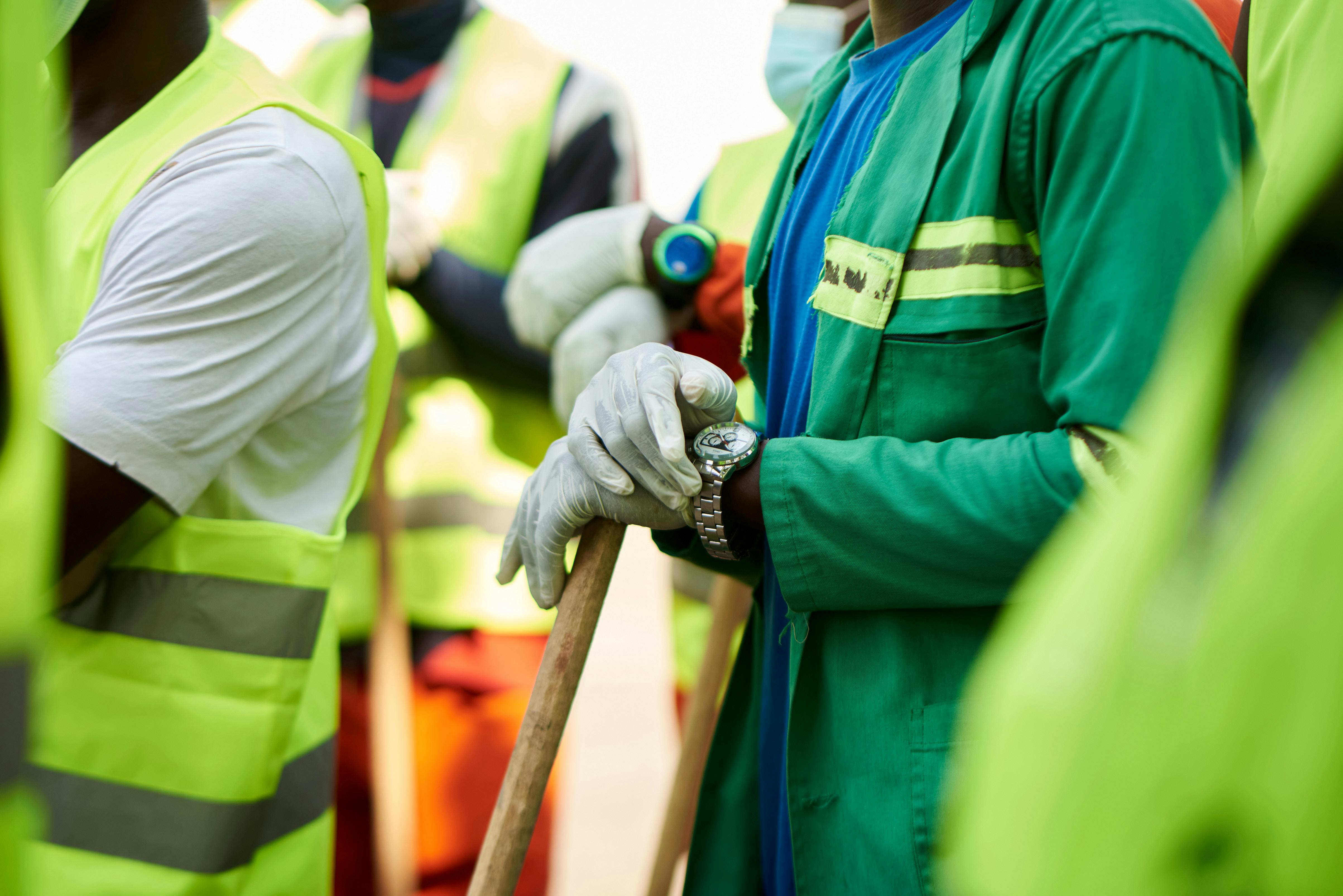 Close-up of construction workers wearing safety vests and gloves in Douala, Cameroon.