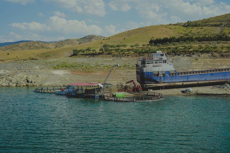 Industrial Machinery On Water And Shipwreck On A Shore