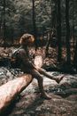 A Man Sitting on a Log in a Forest