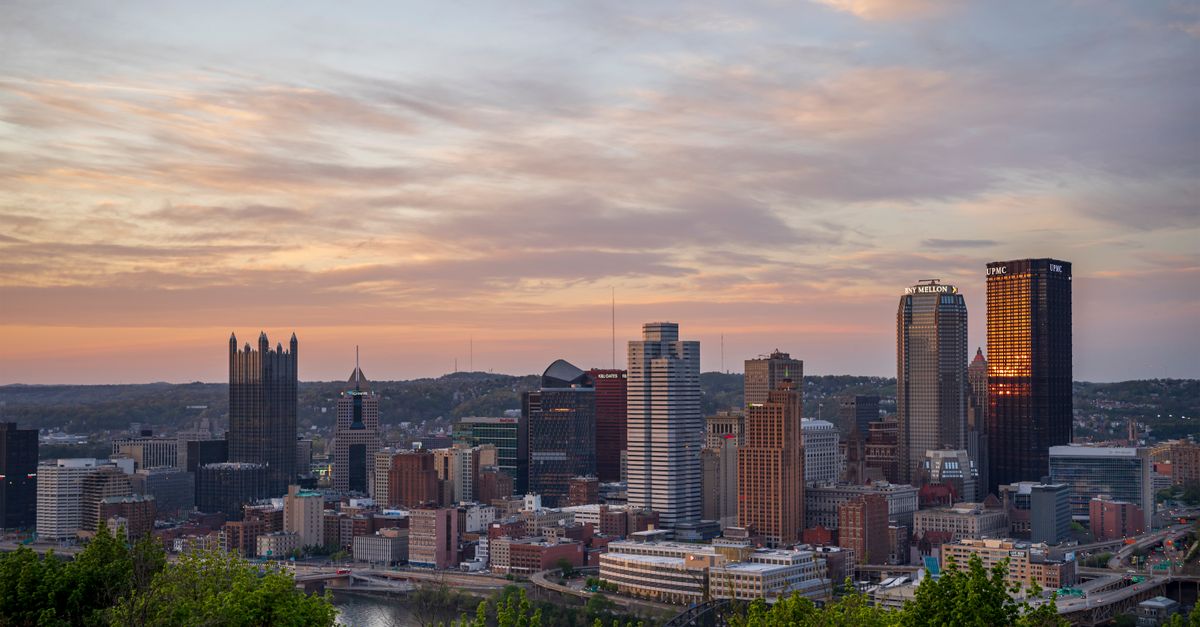 Stunning aerial view of Pittsburgh skyline with vibrant sunset colors in the sky.
