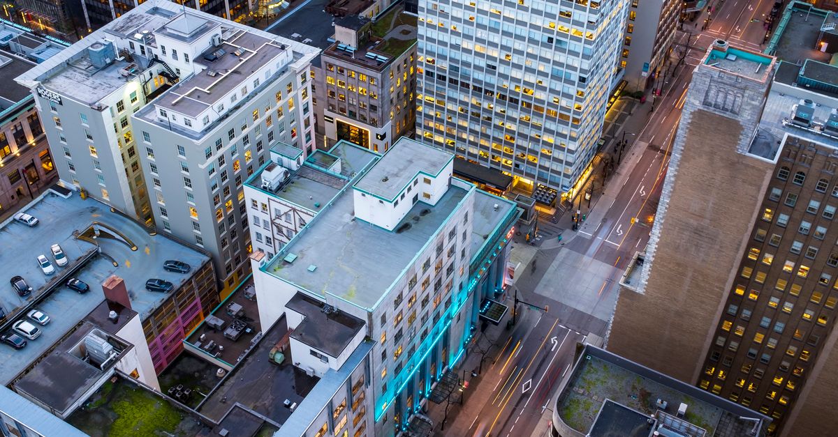 Explore the aerial view of downtown Vancouver's illuminated cityscape at twilight, showcasing its modern architecture and urban streets.