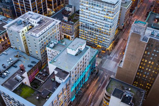 Explore the aerial view of downtown Vancouver's illuminated cityscape at twilight, showcasing its modern architecture and urban streets.