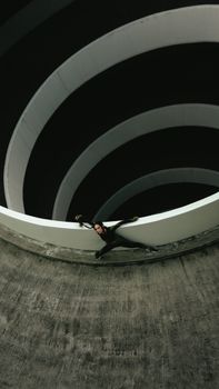 Woman leaning on a spiral structure in an abstract setting, unique perspective.
