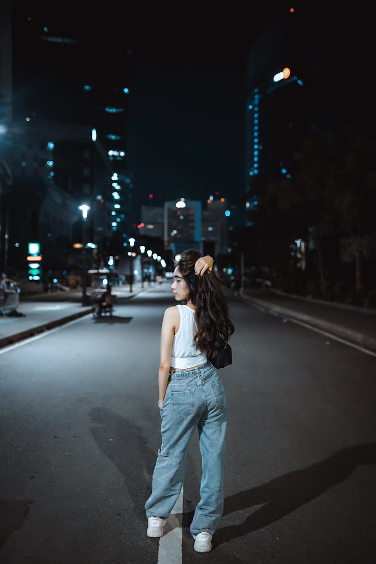 Teenage Girl Posing In Middle Of Road In City At Night