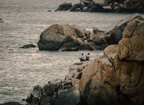 People Sitting on Rocks near Sea