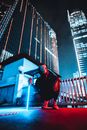 Masked Person Crouching in City Street at Night