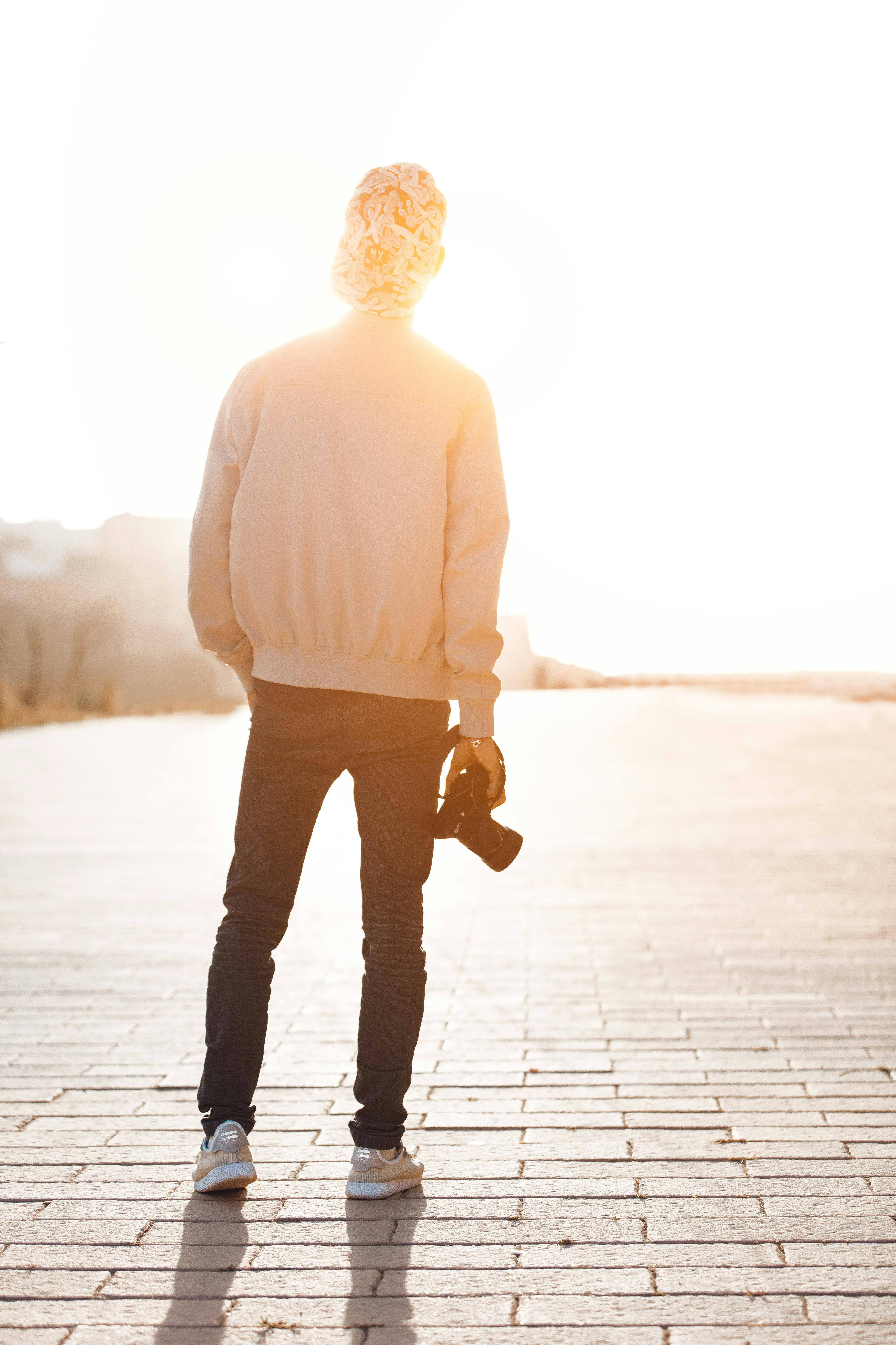 Boy Standing While Holding Camera Overlooking Sunlight at Daytime