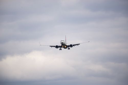 Free Commercial jet airplane flying amidst a cloudy sky, showcasing aviation dynamics. Stock Photo