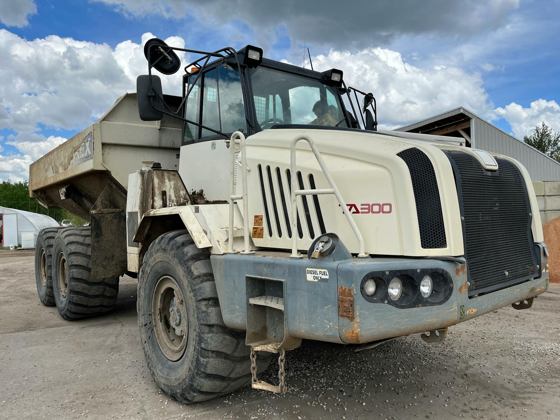 Large mining dump truck parked outdoors at a construction site under a cloudy sky.