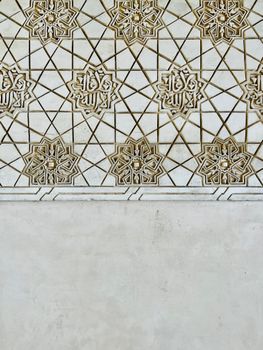 Detailed geometric patterns on a textured wall showcasing Islamic art in a vertical shot.