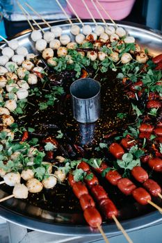 Delicious grilled skewers with herbs in a vibrant street food setting.