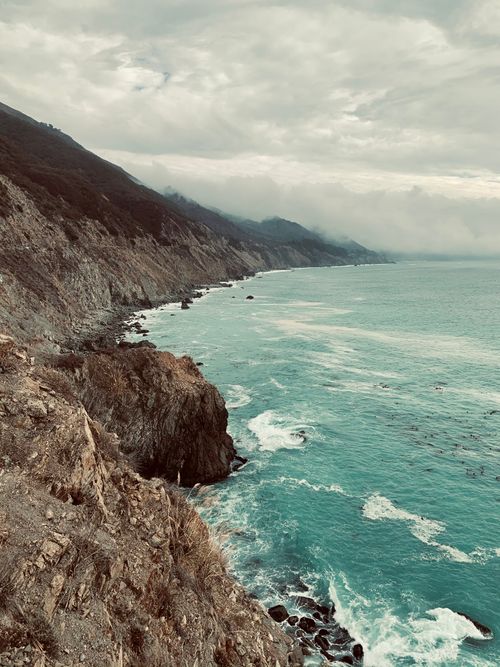 Free Dramatic coastal view with rocky cliffs and turbulent sea under a cloudy sky Stock Photo