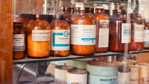 A collection of vintage pharmacy bottles on wooden shelves, showcasing old medicine containers.