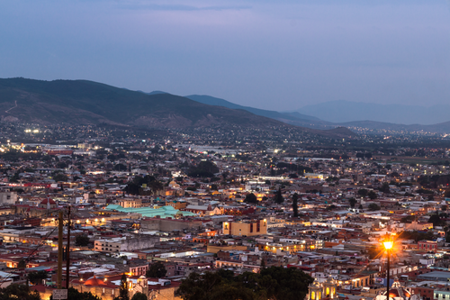 Free Beautiful cityscape at dusk featuring luminous city lights against a mountainous backdrop. Stock Photo