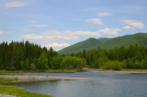 Free A tranquil river scene with lush forests and rolling hills under a blue sky. Perfect nature scenery. Stock Photo