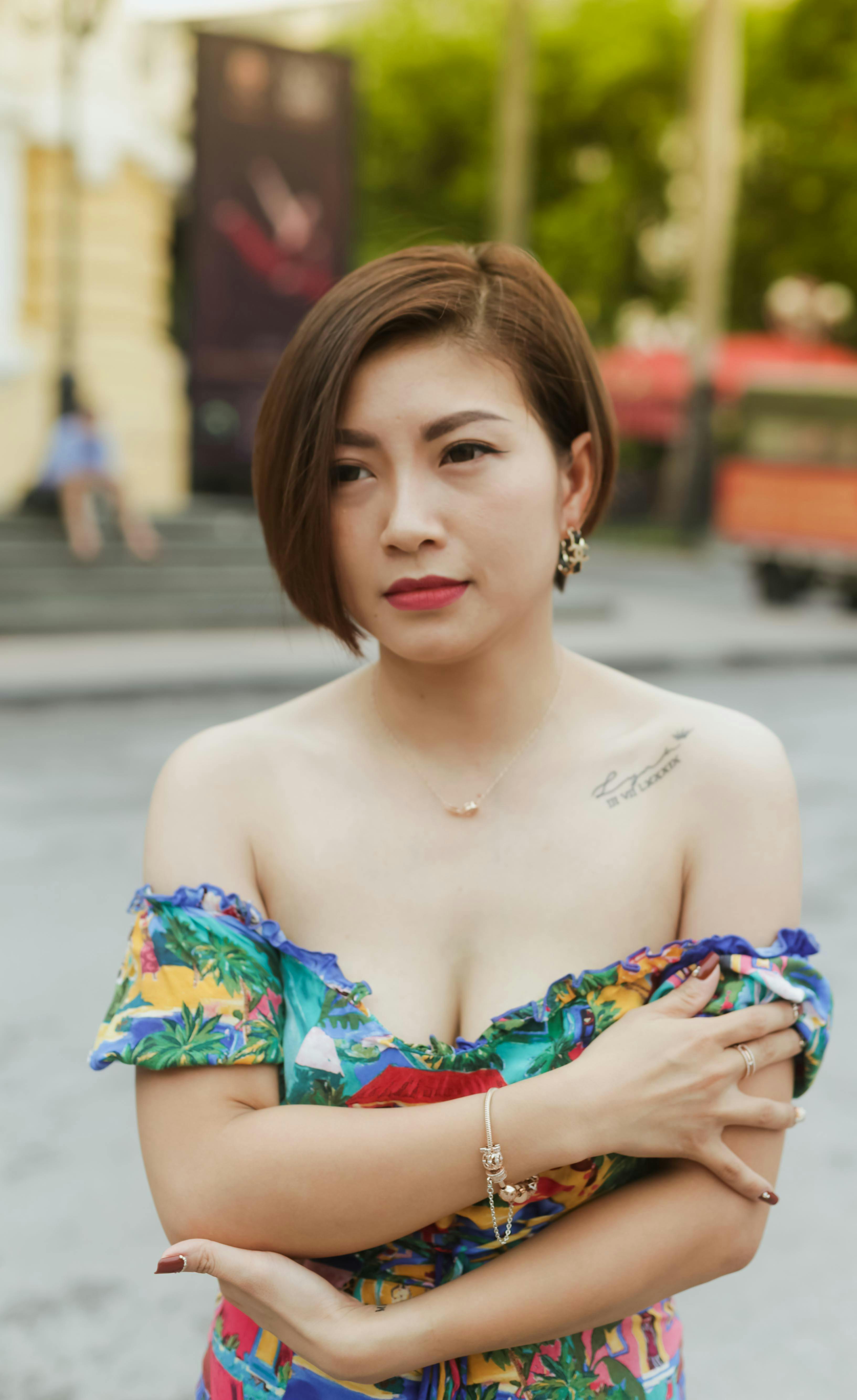 Asian woman in a vibrant off shoulder dress outdoors, exuding elegance and style.
