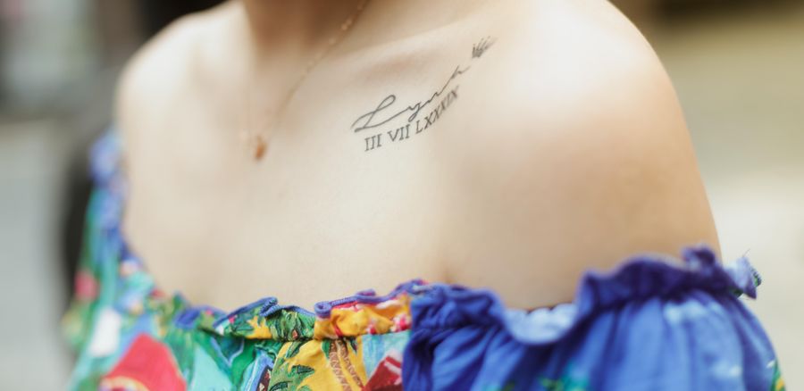 Script tattoo across a woman's shoulder and collarbone
