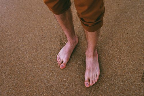 Free Close-up of a person relaxing barefoot on a sandy beach, capturing summer vibes. Stock Photo