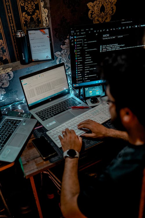 A Person Using a Computer Keyboard in Front of a Laptop