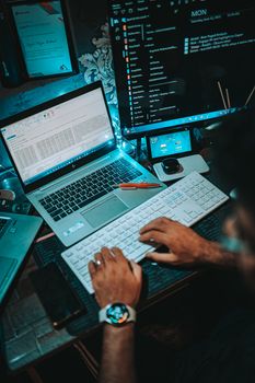 A person working on a dual-monitor setup with a laptop and keyboard in an office environment.