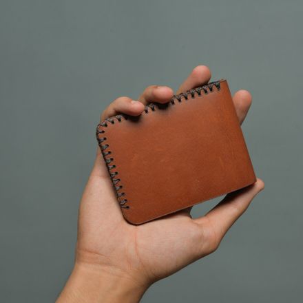 Hand holding a stitched leather bifold wallet — photo by Candy Flipping on Pexels