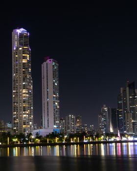 Stunning night view of Panamá City's skyline with illuminated high-rise buildings reflecting on the water.