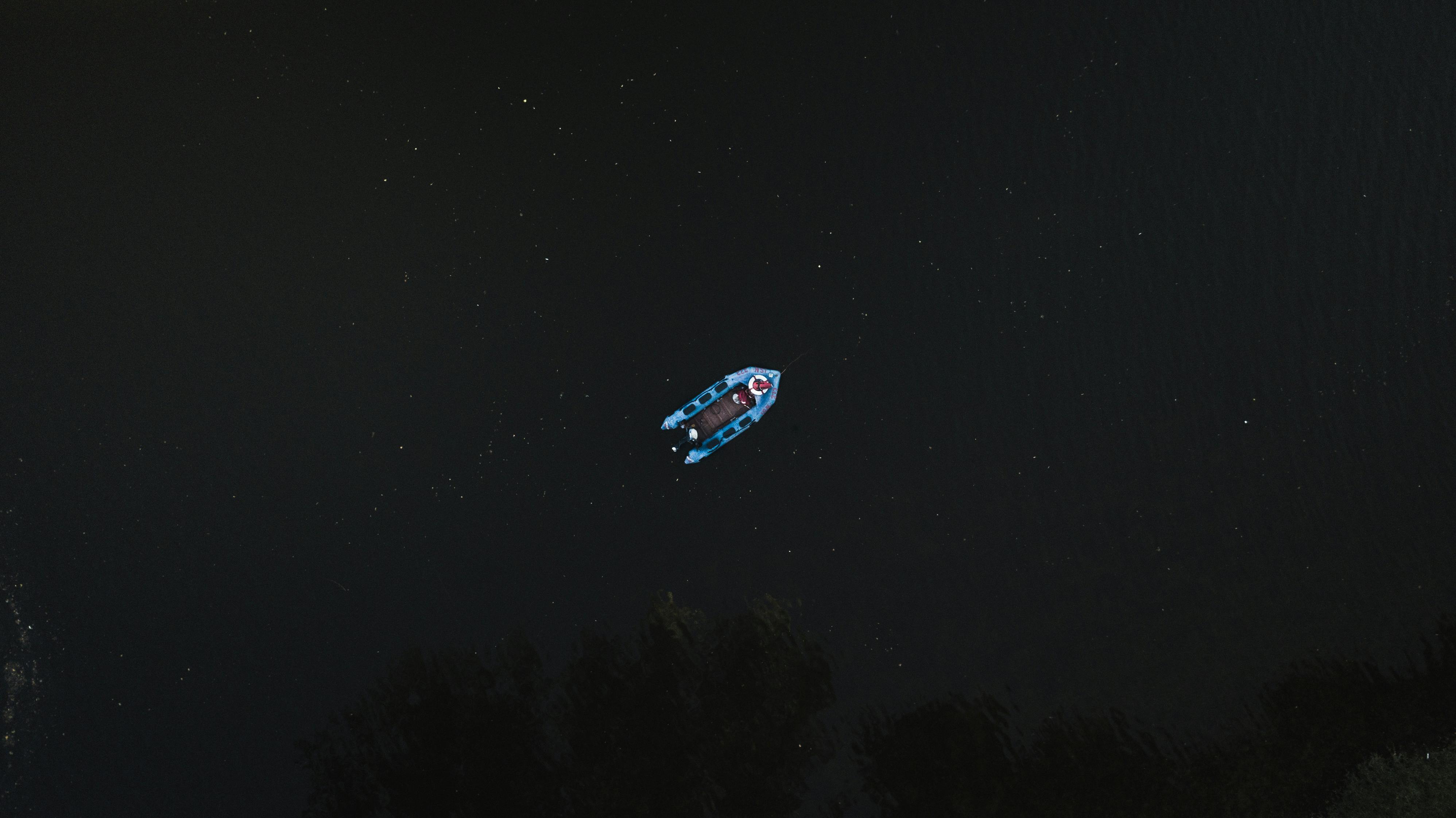 一张夜间航拍的黑暗河流上的船只照片