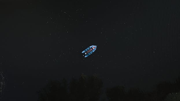 一张夜间航拍的黑暗河流上的船只照片