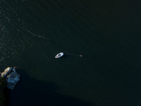 无人机从空中俯瞰广阔的海洋，捕捉到一艘孤独的帆船，画面展现了宁静与探索的意境