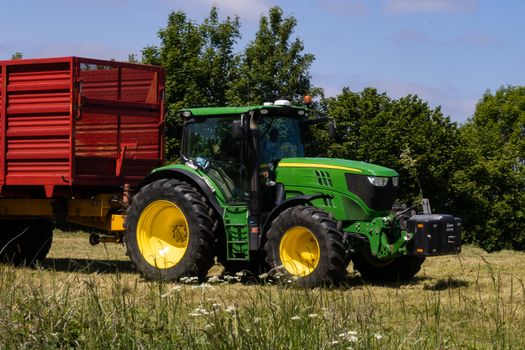 John Deere tractor pulling a trailer on meadow
