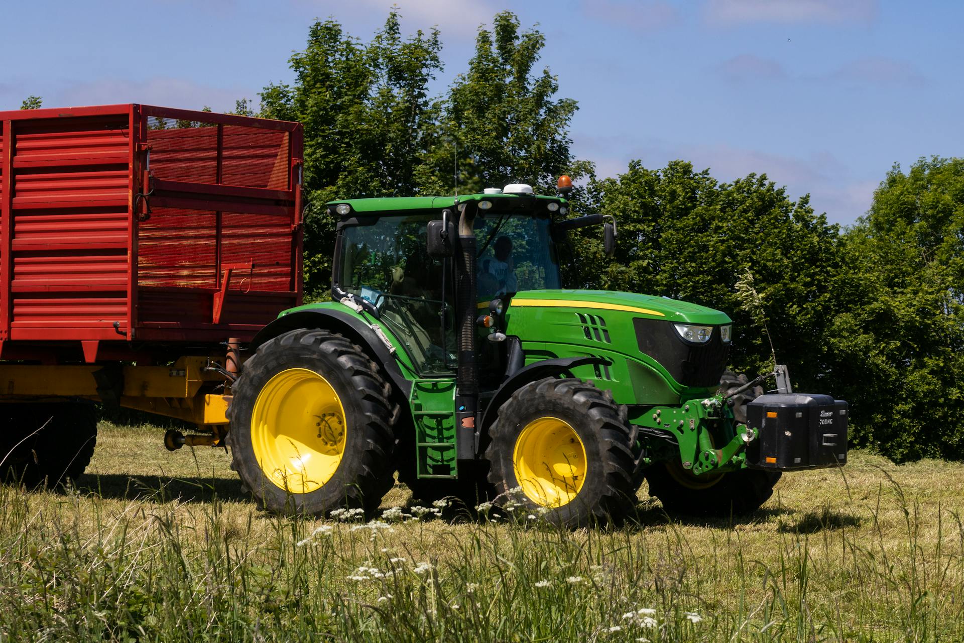 John Deere tractor pulling a trailer on meadow