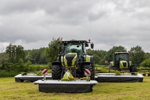Green Tractors on Agricultural Field Under White Sky