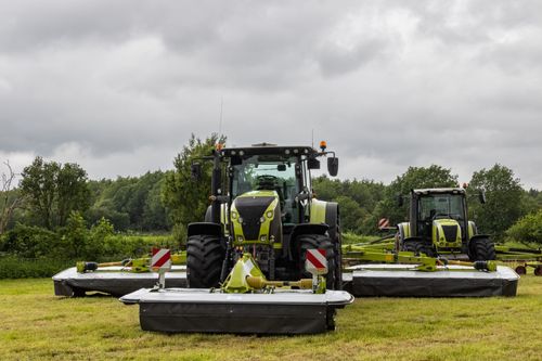 Free Two tractors in a field ready for plowing, set against a cloudy sky. Stock Photo