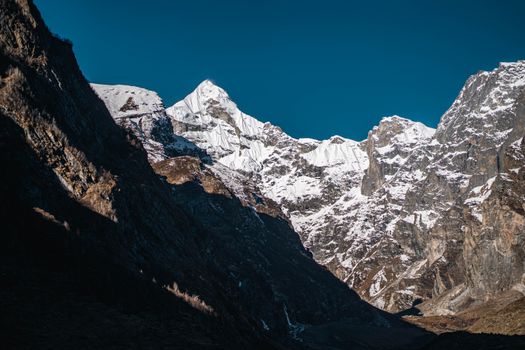 Captivating view of snow-covered mountain peaks against a clear blue sky, exemplifying winter outdoors beauty.